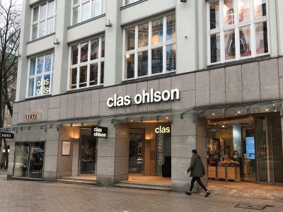 Clas Ohlson Laden in Hamburgs Innenstadt, Eingang in den Laden mit Blick auf die Sandsteinfassade des vornehmen Hauses am Gerhard-Hauptmann-Platz